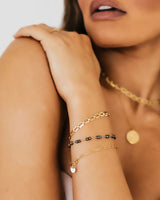Phoebe 14k gold-filled paperclip bracelet on model's wrist layered with two other bracelets