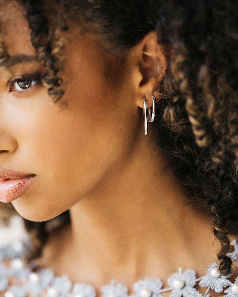 Sequoia side profile wearing stacked large and small Cami Oval Hoop earrings in Sterling silver metal