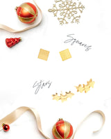 Star Climber and Mini Square Stud earrings in 14k gold on white background with ribbons and ornaments