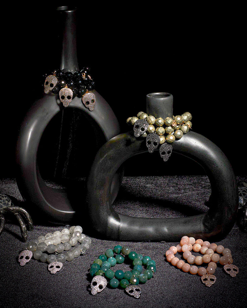 House of Dark Desire jeweled skull bracelets on black cloth with haunted bottles