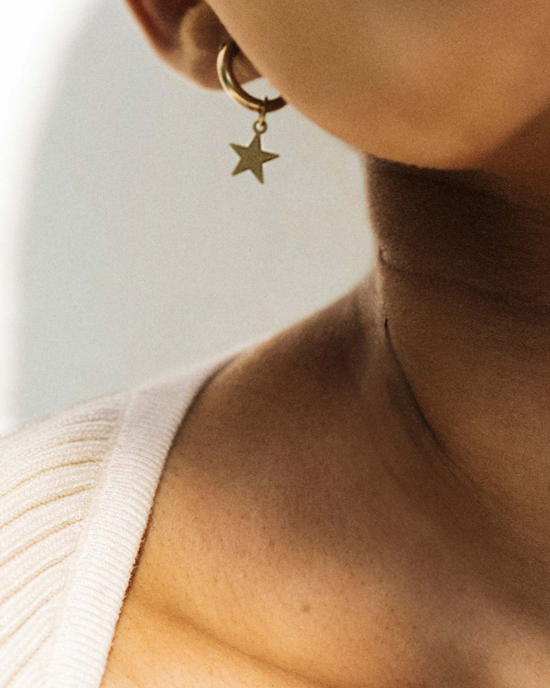 Close Up of a Model Wearing 14K Gold-Filled Star Charm Mini Huggie Hoops