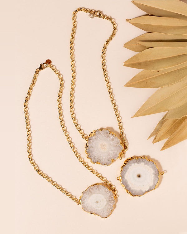 3 Zuri Solar Quartz necklaces flat lay on peach